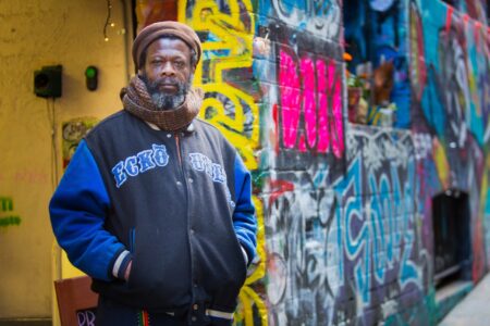 A cafe owner standing outside his business in Melbourne’s iconic Hosier Lane surrounded by vibrant street art. Portrait of a cafe owner standing outside his business in Hosier Lane, Melbourne, surrounded by colourful graffiti and street art.