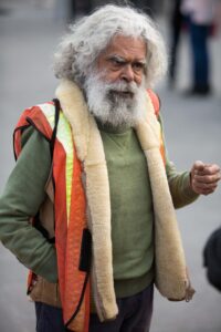 Uncle Jack Charles speaking with attendees during an Indigenous rights rally in Melbourne. Portrait of Uncle Jack Charles, an Indigenous Australian elder and activist, speaking with people at an Indigenous rights rally in Melbourne.